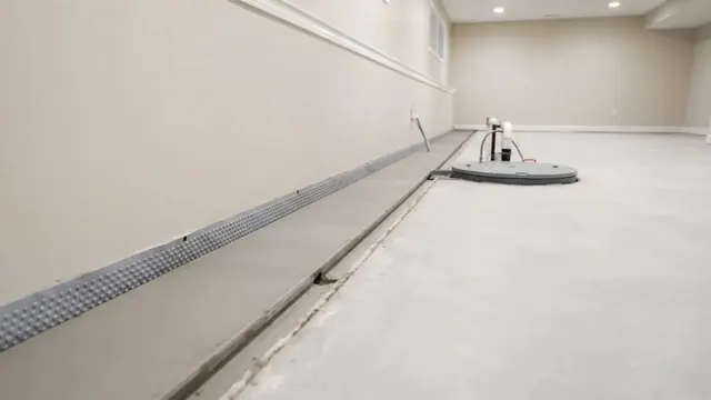 Finished basement with a perimeter drain channel along the wall and a sump pit cover