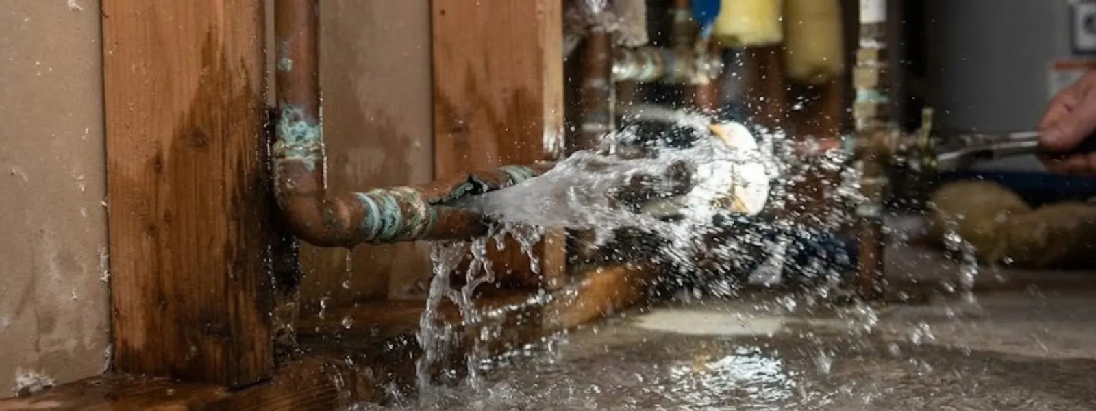 Water spraying from a leaking copper pipe in a framed wall